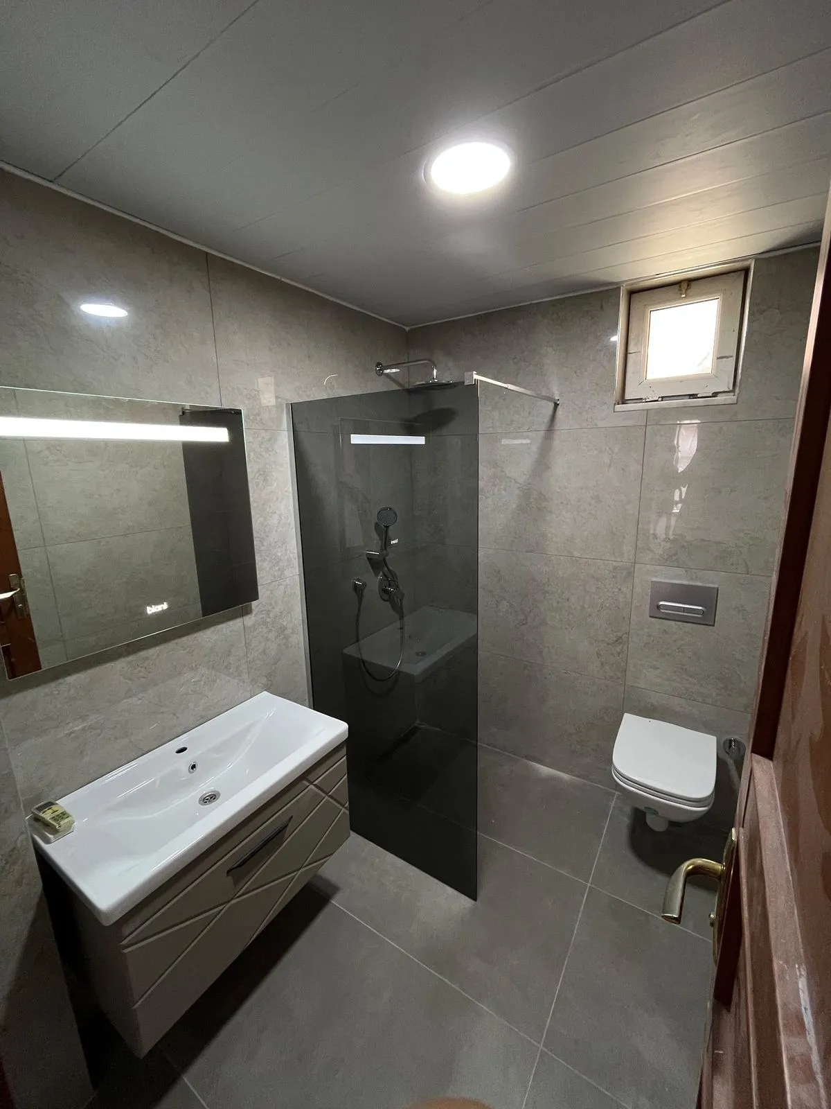 Gri seramikli banyo ve füme cam duş paneli