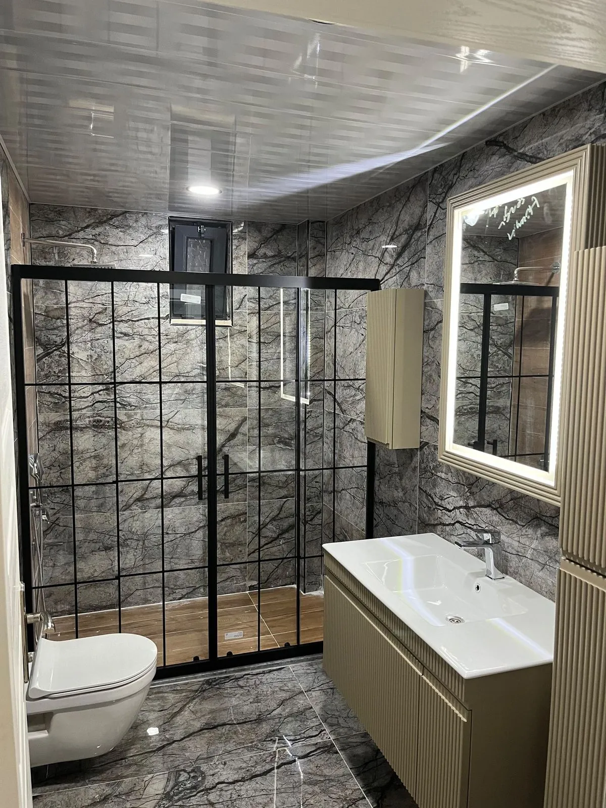Koyu mermer desenli banyo ve siyah çerçeveli duşakabin